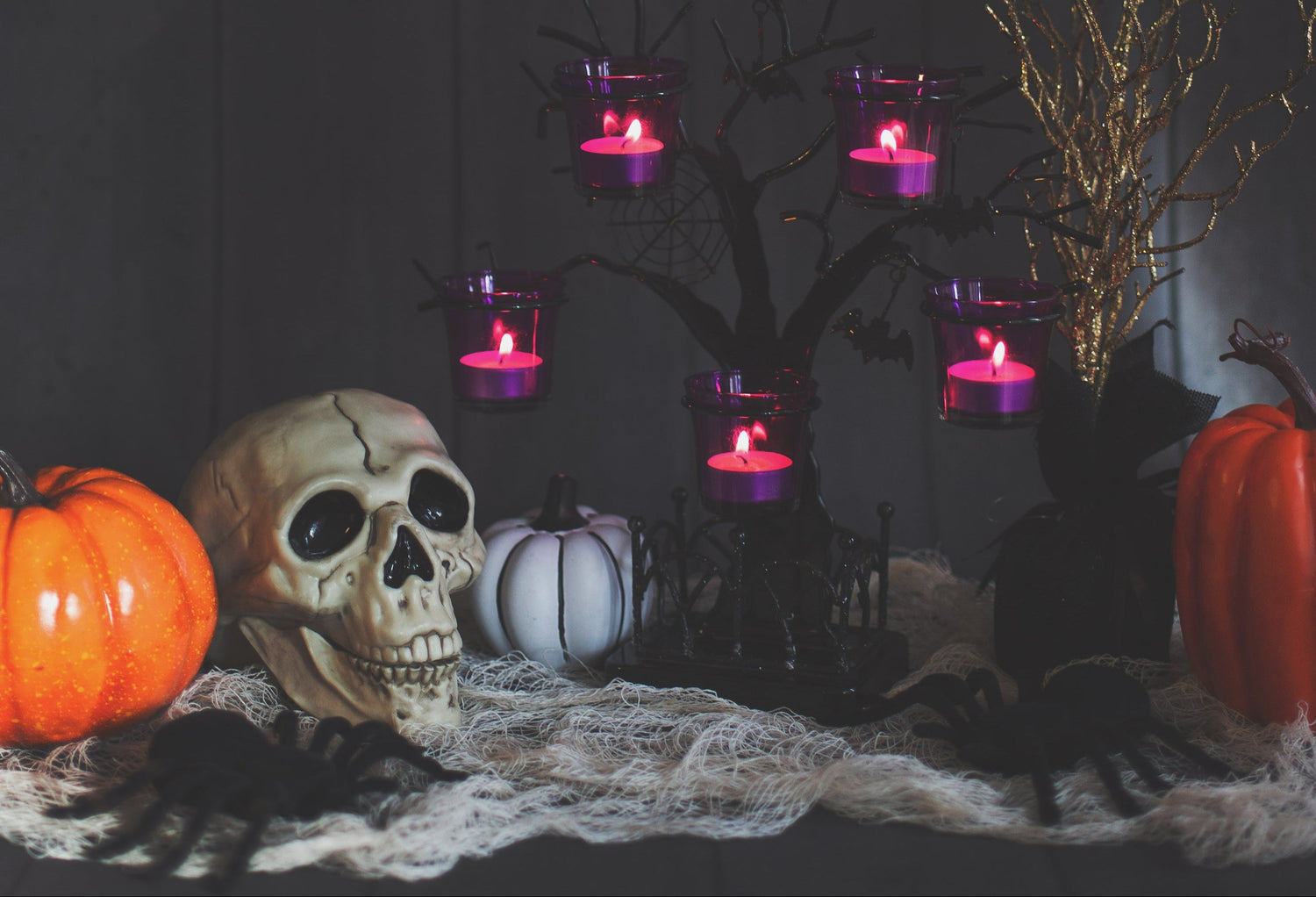 Halloween-themed setup with skull, pumpkins, and candles on a dark background