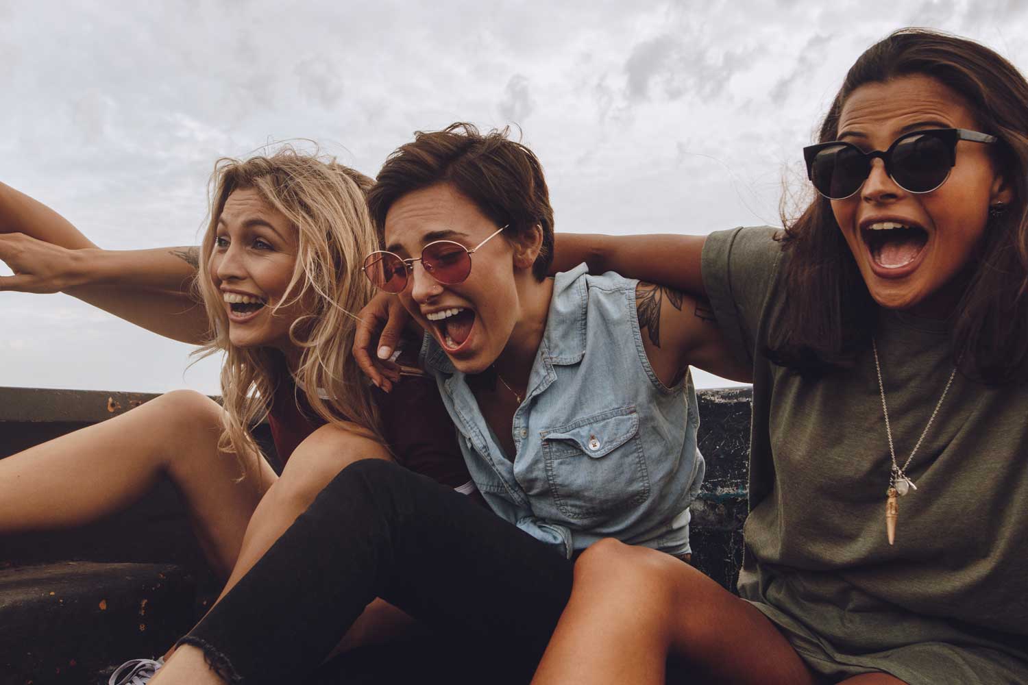 Three best girl friends in a truck bed, laughing together.
