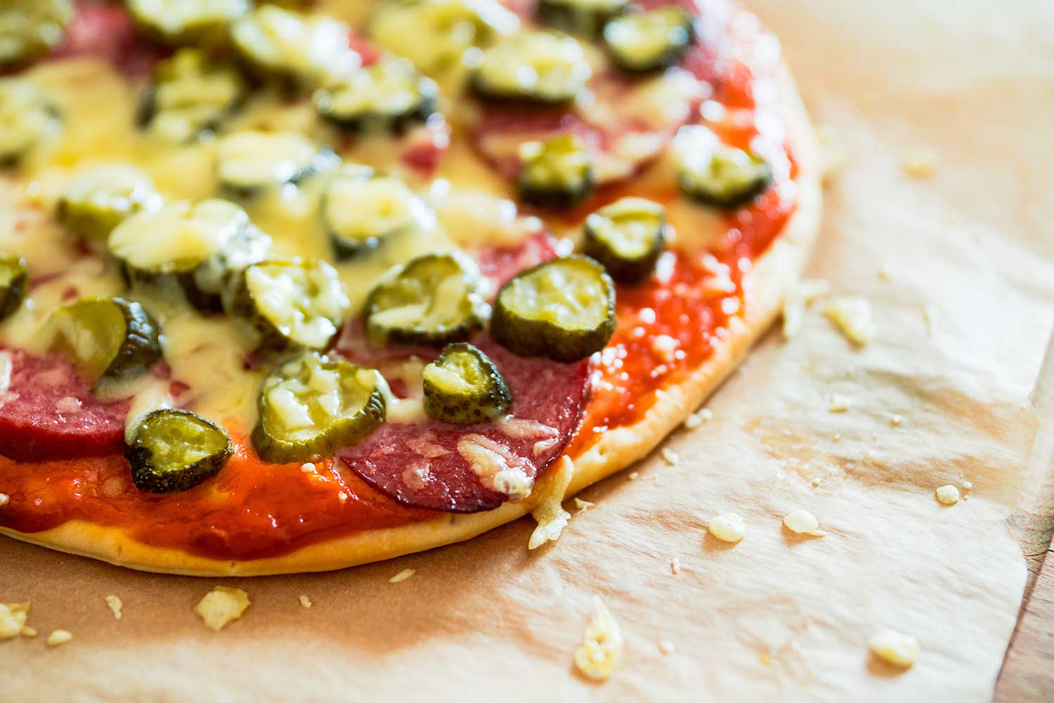 A savory looking thin crust pizza topped with cheese, pepperoni and slices of dill pickles.