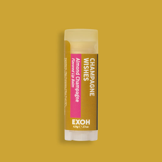Product photo of almond champagne flavored lip balm "Champagne Wishes" by EXOH on gold colored background.