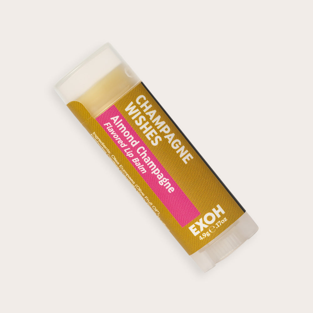 Product photo of almond champagne flavored lip balm "Champagne Wishes" by EXOH on grey background.