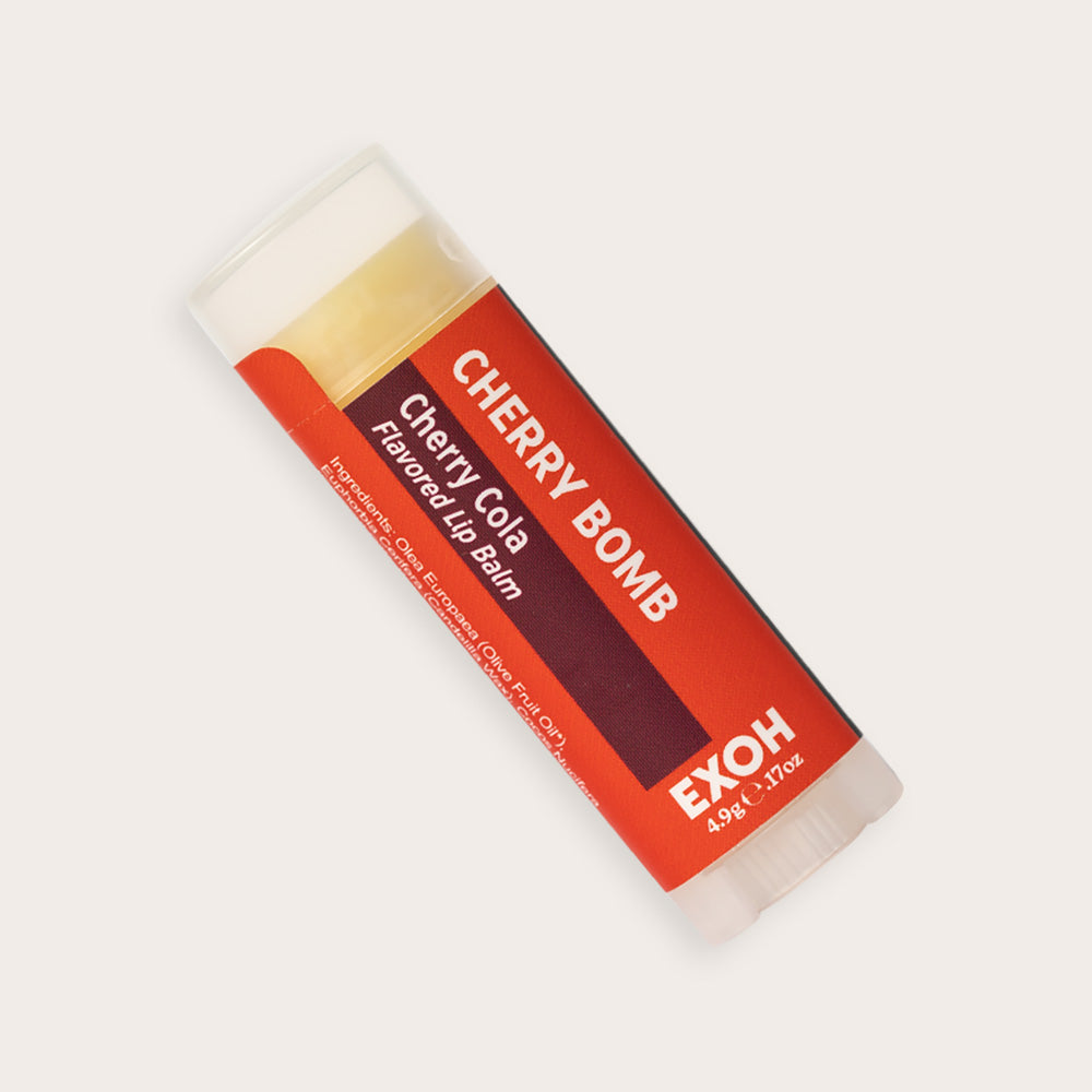 Product photo of cherry cola flavored lip balm "Cherry Bomb" by EXOH on grey background.