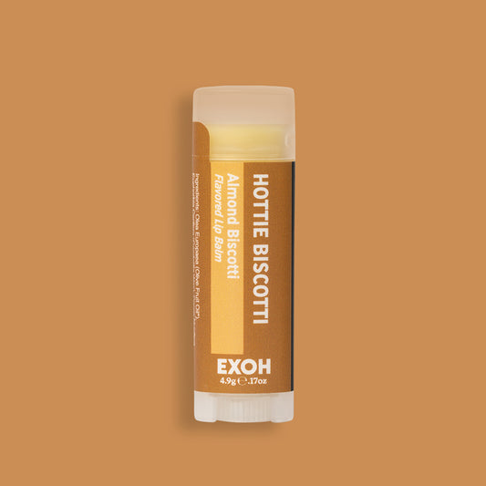 Product photo of almond biscotti flavored lip balm "Hottie Biscotti" by EXOH on toasted brown background.