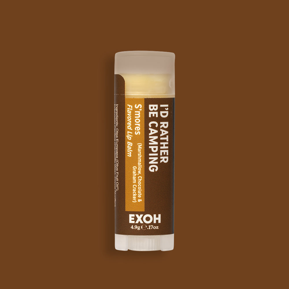 Product photo of s'mores flavored lip balm "I'd Rather Be Camping" by EXOH on chocolate brown background.