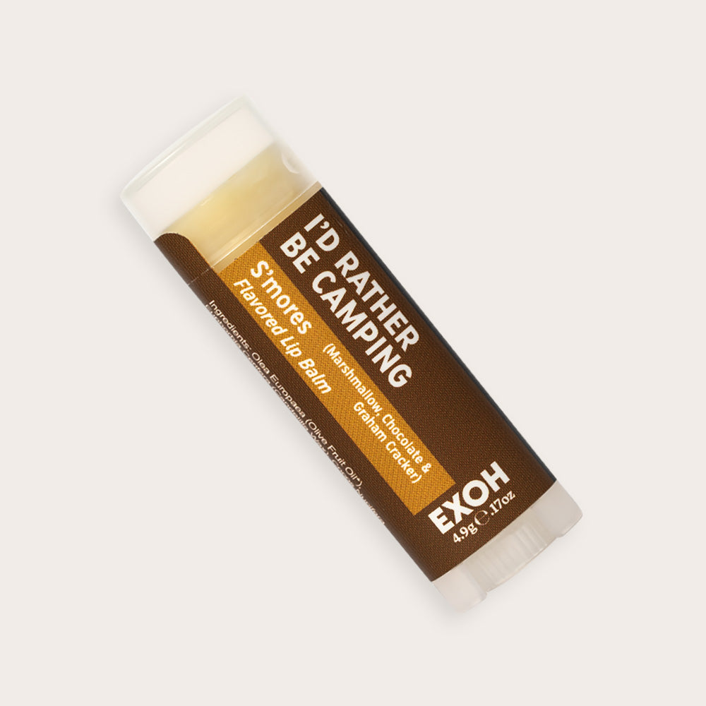 Product photo of s'mores flavored lip balm "I'd Rather Be Camping" by EXOH on grey background.