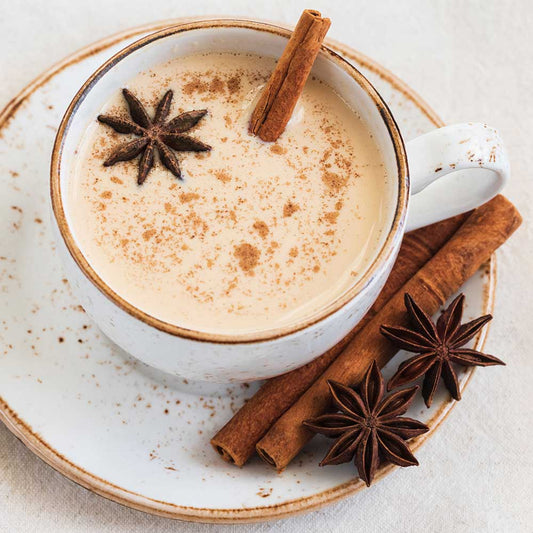 Spiced chai tea latte in a mug with cinnamon sticks and anise, indicating flavor of "Spiced Chai, Baby" flavored lip balm by EXOH.